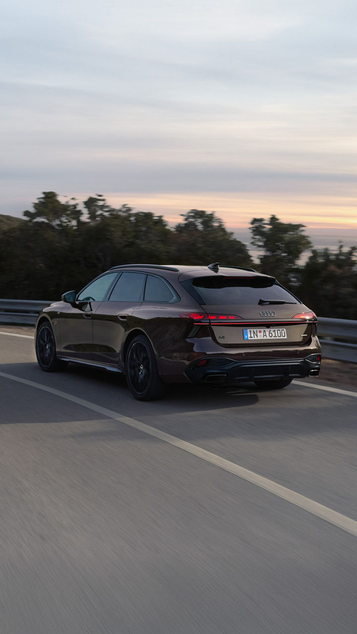 Rückansicht des neuen Audi A6 Avant auf der Straße in abendlichem Licht.