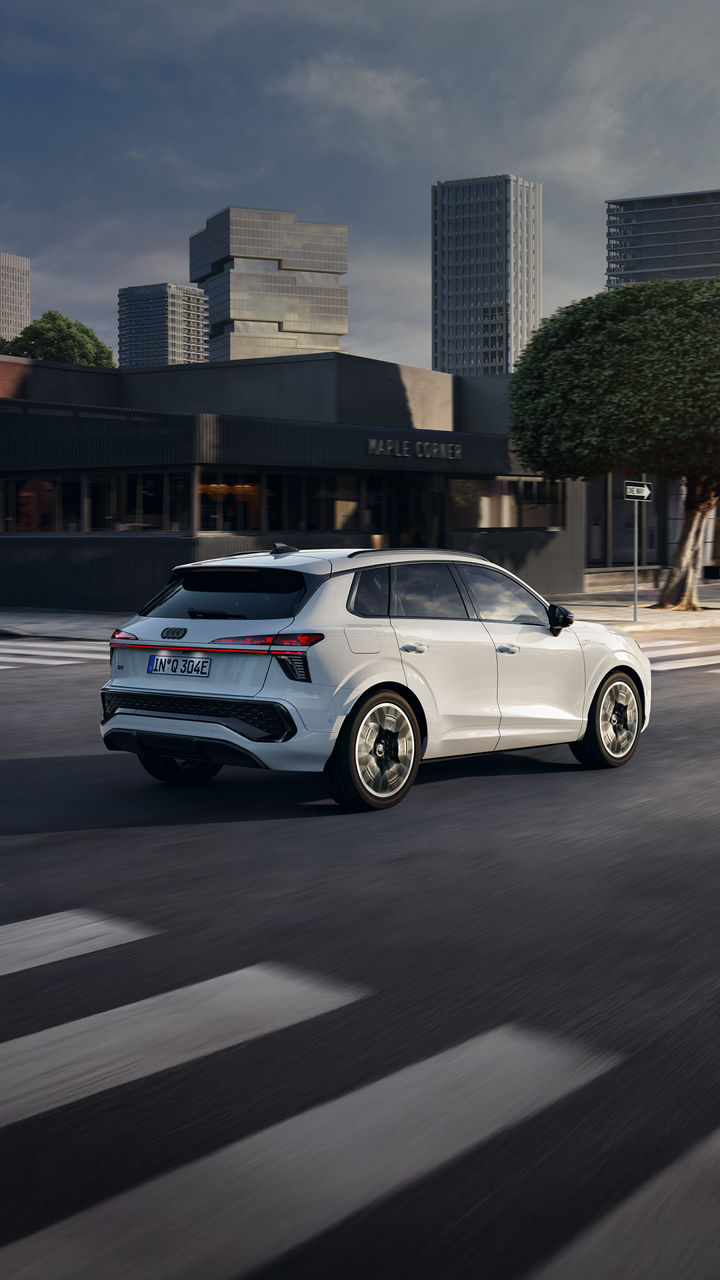 Ein weißer Audi Q3 SUV e-hybrid auf der Straße in urbanem Setting.