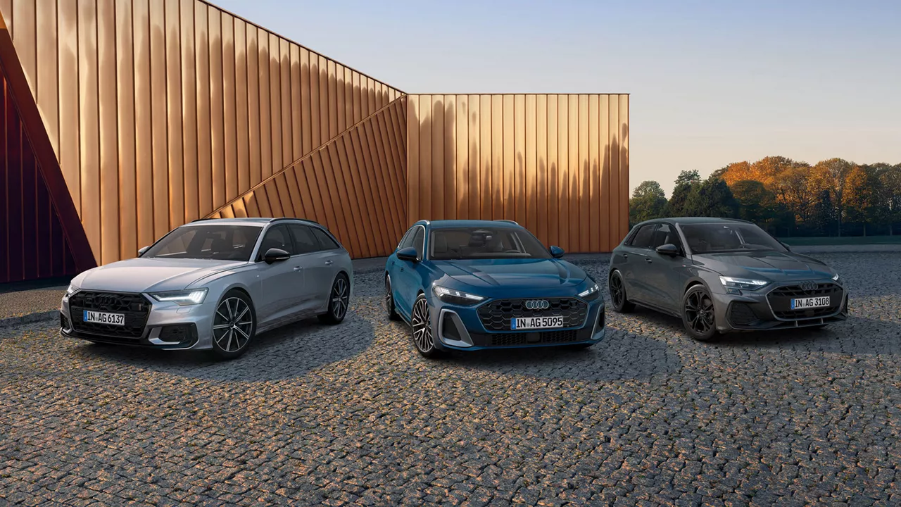 Drei Audi-Fahrzeuge nebeneinander auf Kiesfläche vor moderner Architektur