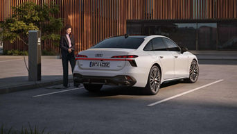 Audi A6 sedan rear view with a woman standing next to the car