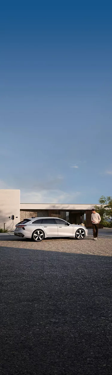 Audi A6 Avant e-hybrid bianca parcheggiata e collegata a una wallbox di ricarica