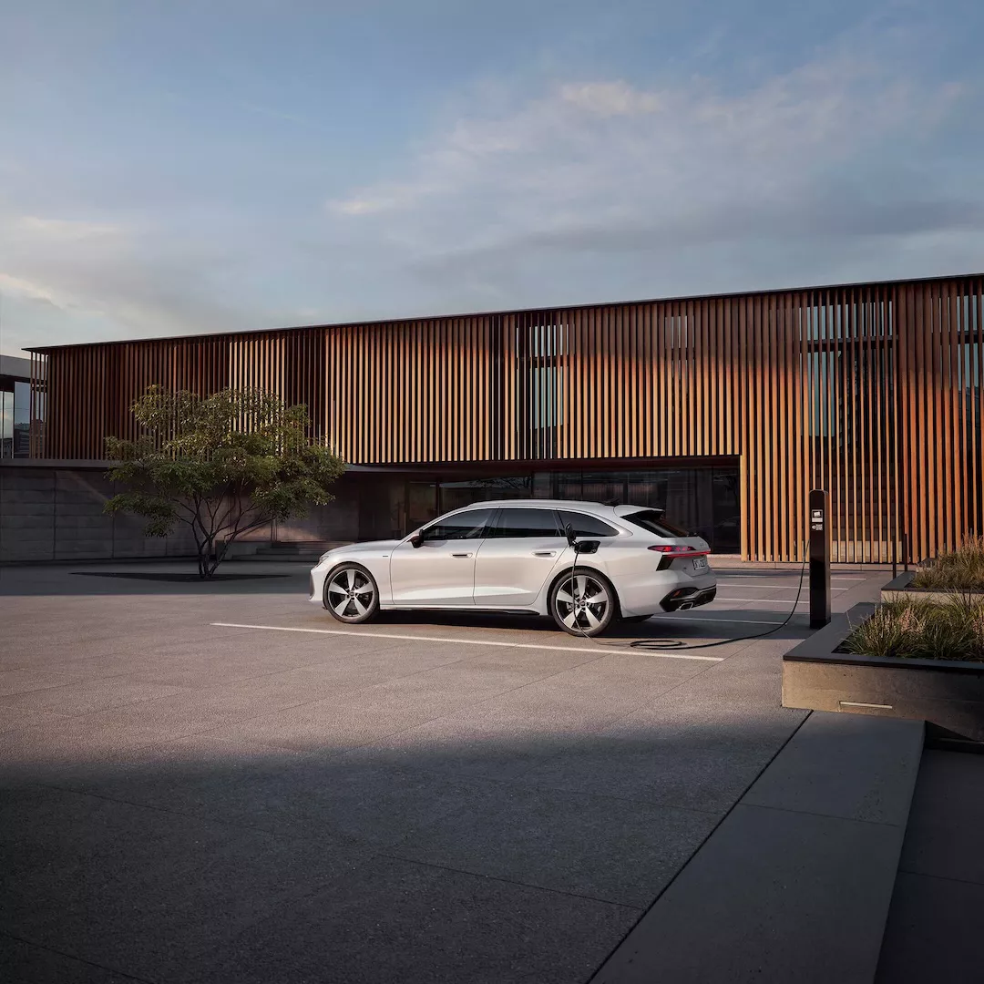 Audi A6 Avant e-hybrid parcheggiata e collegata a una colonnina di ricarica