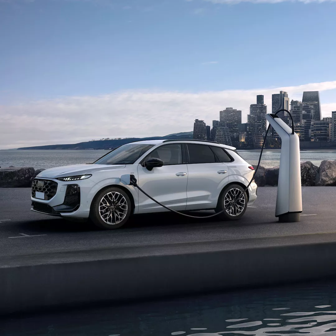 Audi Q3 e-hybrid parcheggiata e collegata a una colonnina di ricarica