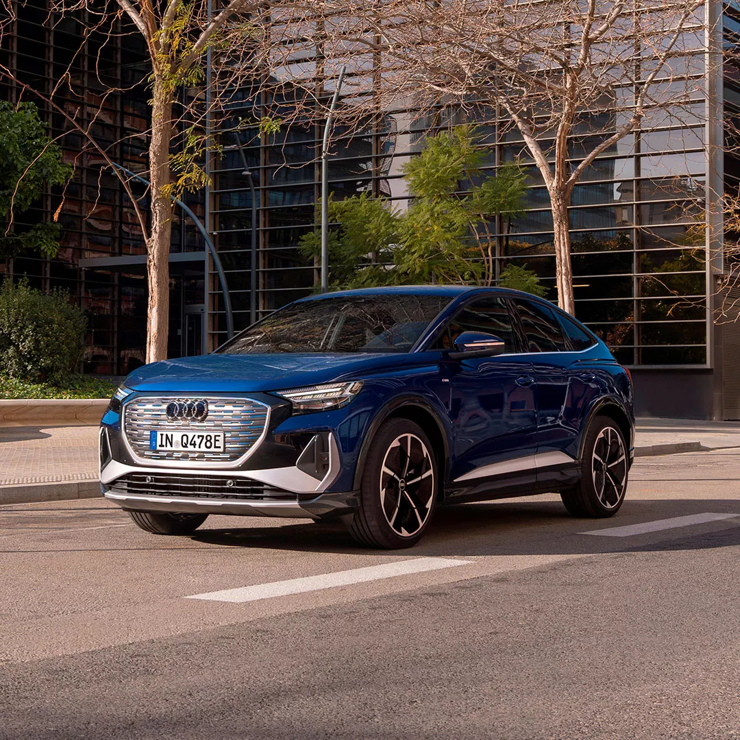 Blauer Q4 e-tron fährt auf einer Straße in einem urbanen Raum.
