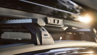Dachträger und Dachbox von Audi auf einem Fahrzeug montiert, mit einer Spiegelung der Sonne.
