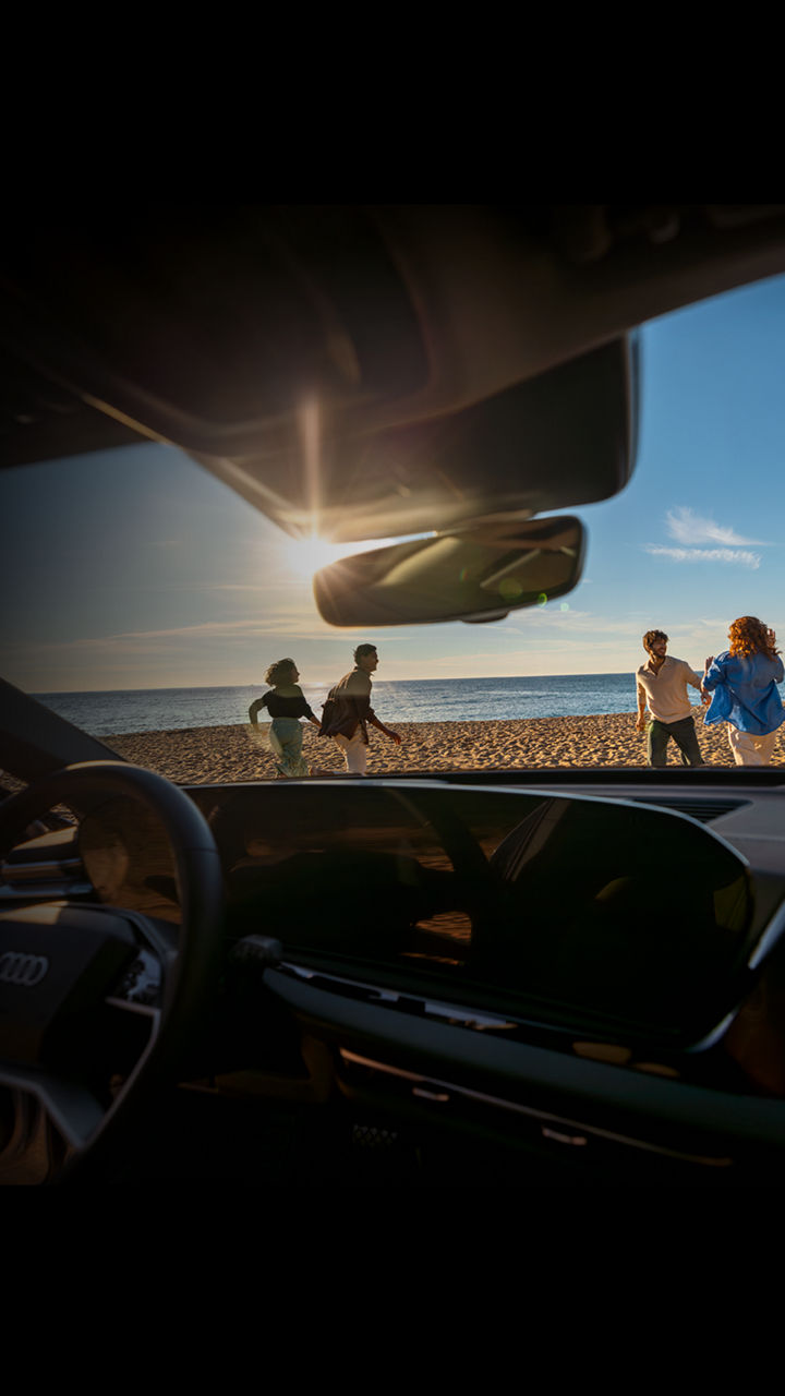 Vier Personen stehen am Strand und werden aus einem Audi heraus fotografiert