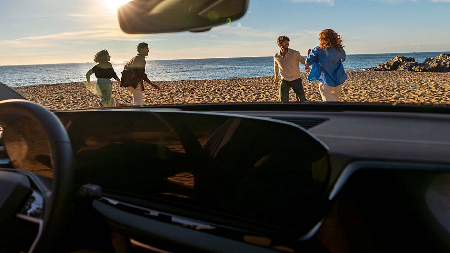 Vier Personen laufen an einem Strand entlang und werden von einem Audi aus fotografiert