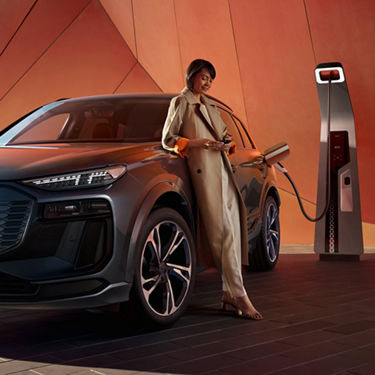 Mujer cargando un Audi SQ6 SUV e-tron en una estación de carga de alta potencia  