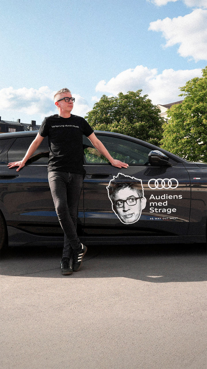 Fredrik Strage lutad mot en mörk Audi A6 e-tron med logotypen för Audiens med Strage