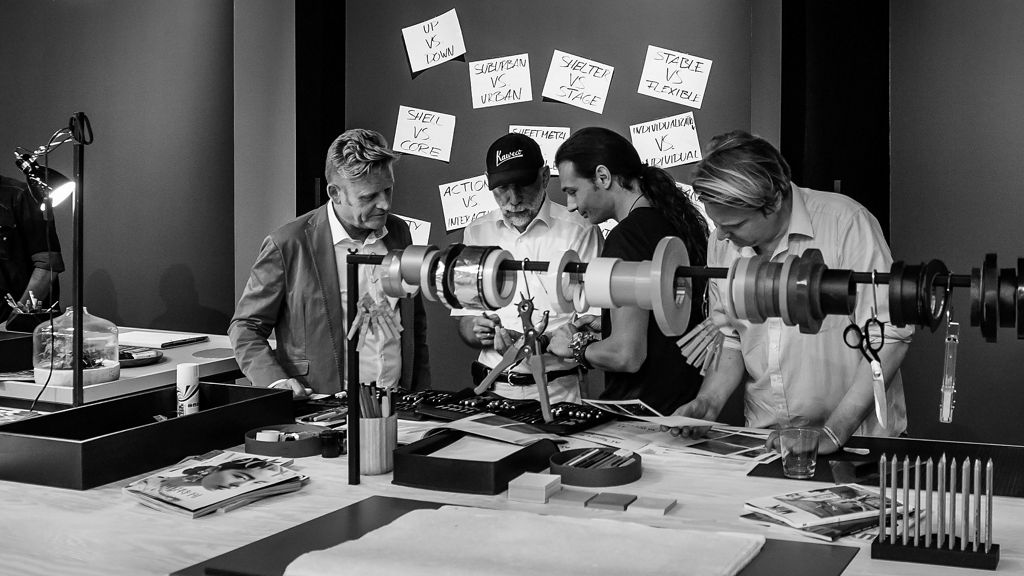 Svartvit bild på fyra män som diskuterar design.