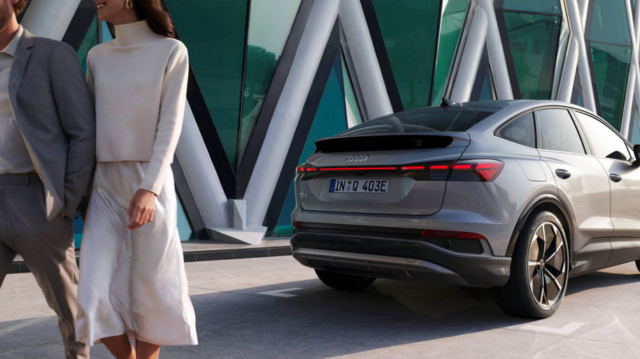 A young couple walking away from a parked Audi Q4 e-tron car