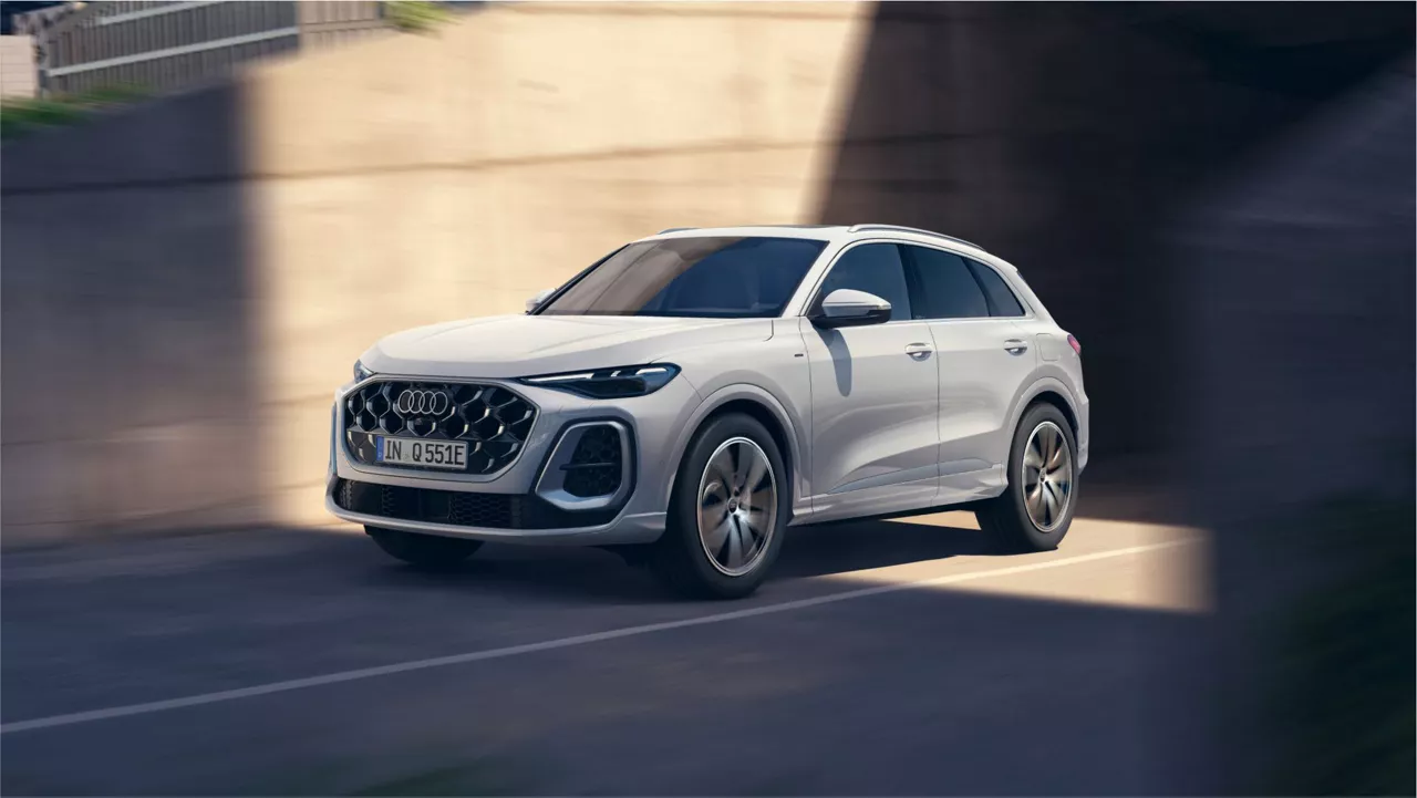 A white Audi Q5 driving through a modern urban environment, showcasing its stylish design and performance.