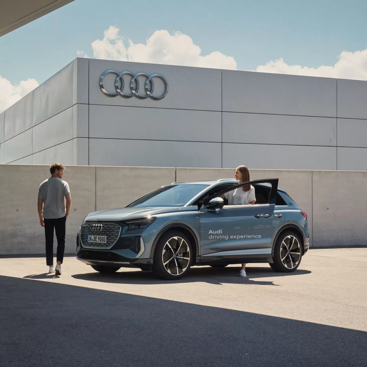 A woman getting in an Audi vehicle with the words Audi Driving Experience on the open door