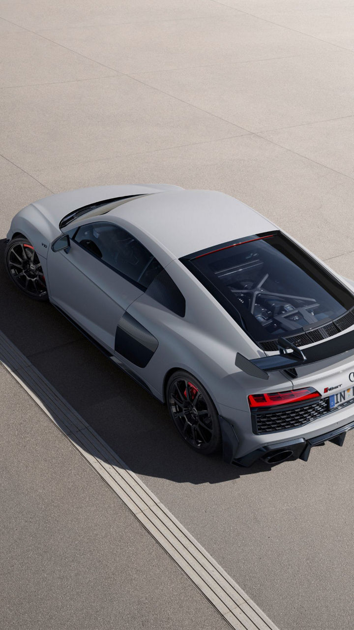 A man walking beside a parked white Audi R8 GT vehicle