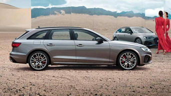 Grey Audi vehicle on desert terrain with a mirror reflecting another car and two people conversing