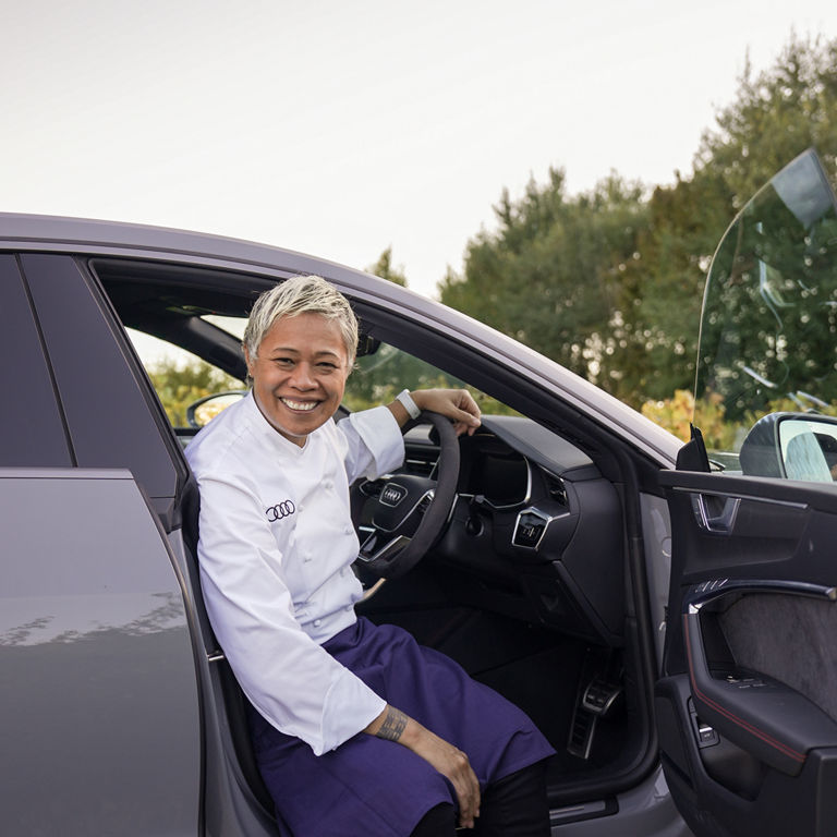 Man wearing chef clothes sitting in an Audi car smiling