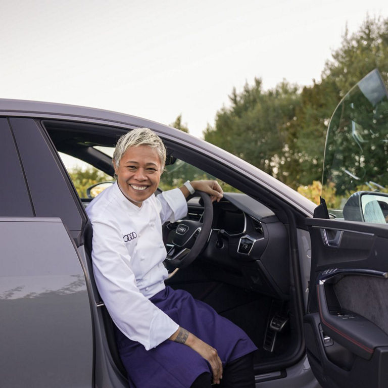 Man wearing chef clothes sitting in an Audi car smiling