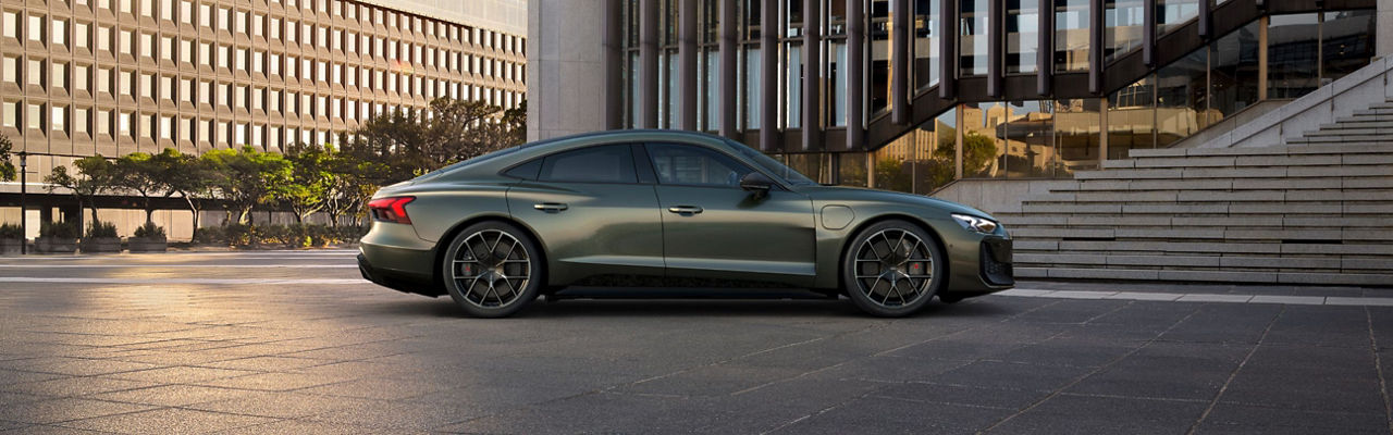 A green Audi sports car outside a modern building.