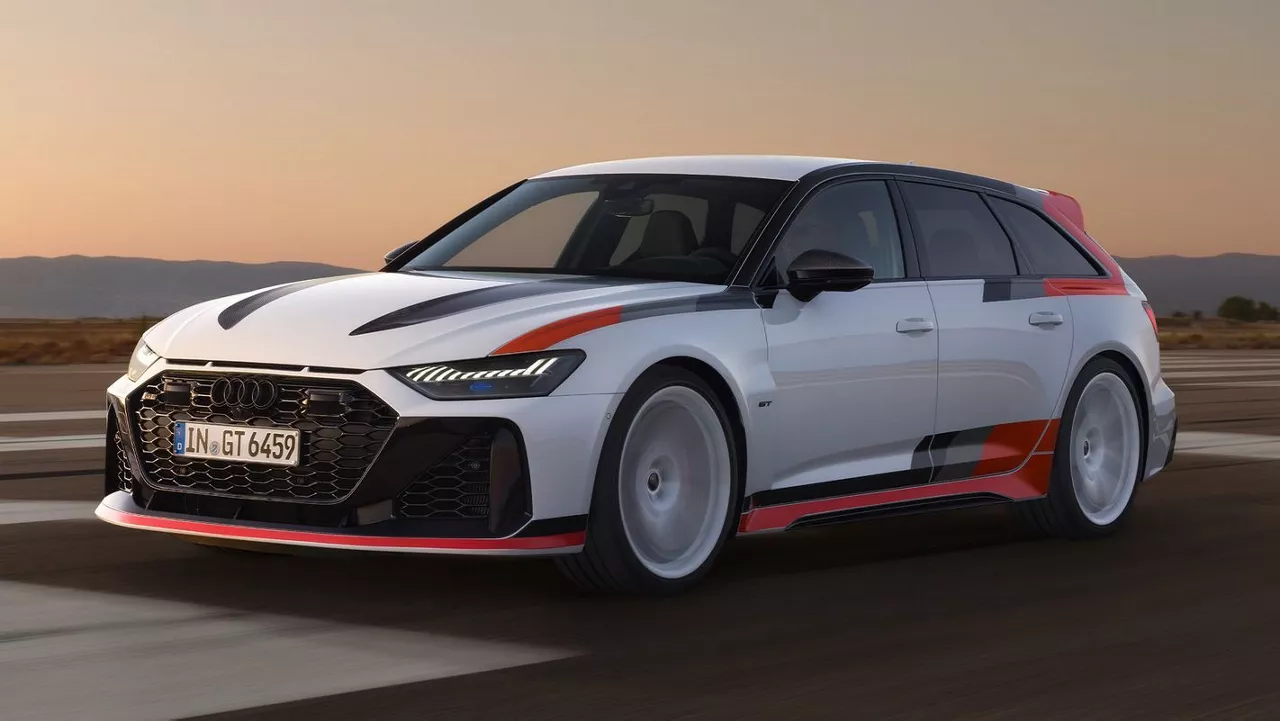 A white and red Audi RS 6 Avant GT vehicle speeding on a road in the early evening