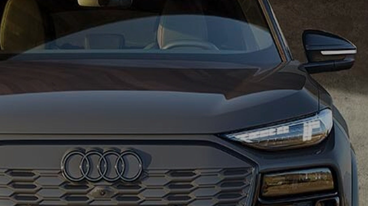 Close up of the front of an Audi car, with Audi logo visible and driver side