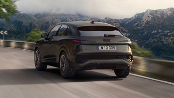 Matte grey Audi Q3 Sportback e-hybrid driving along a mountain road with rocky hills in the background.
