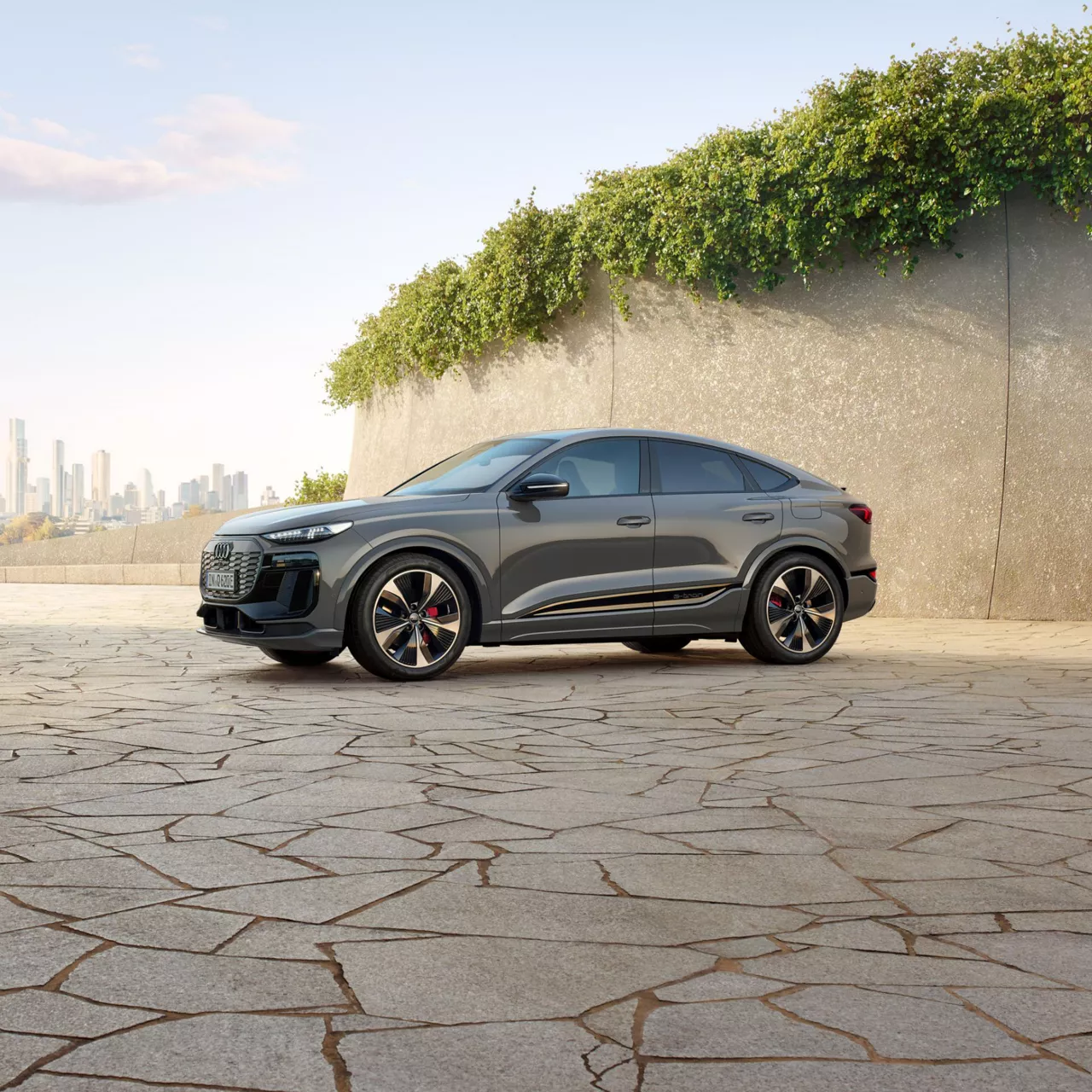 Grey Audi Q6 e-tron  parked on stone with a cityscape background