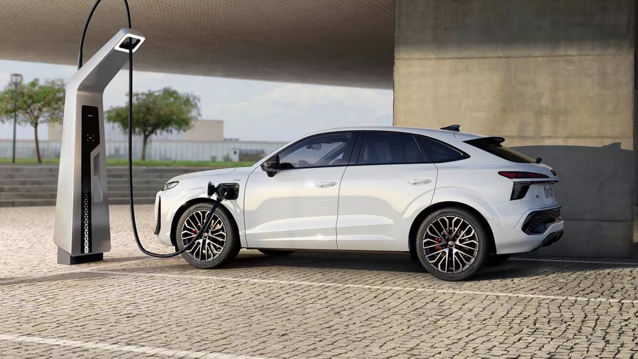 White Audi Q3 Sportback e-hybrid plugged into a modern charging station in an urban outdoor setting.