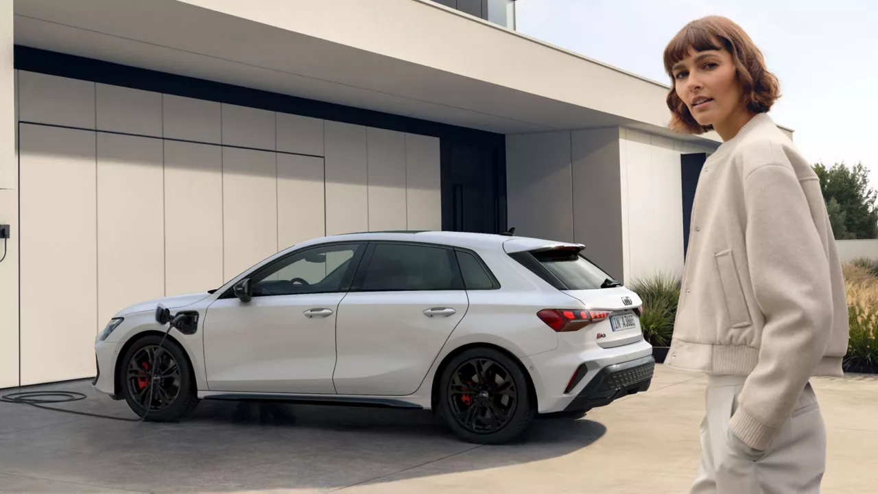 person standing in drive way in front of white Audi A3 TFSI e