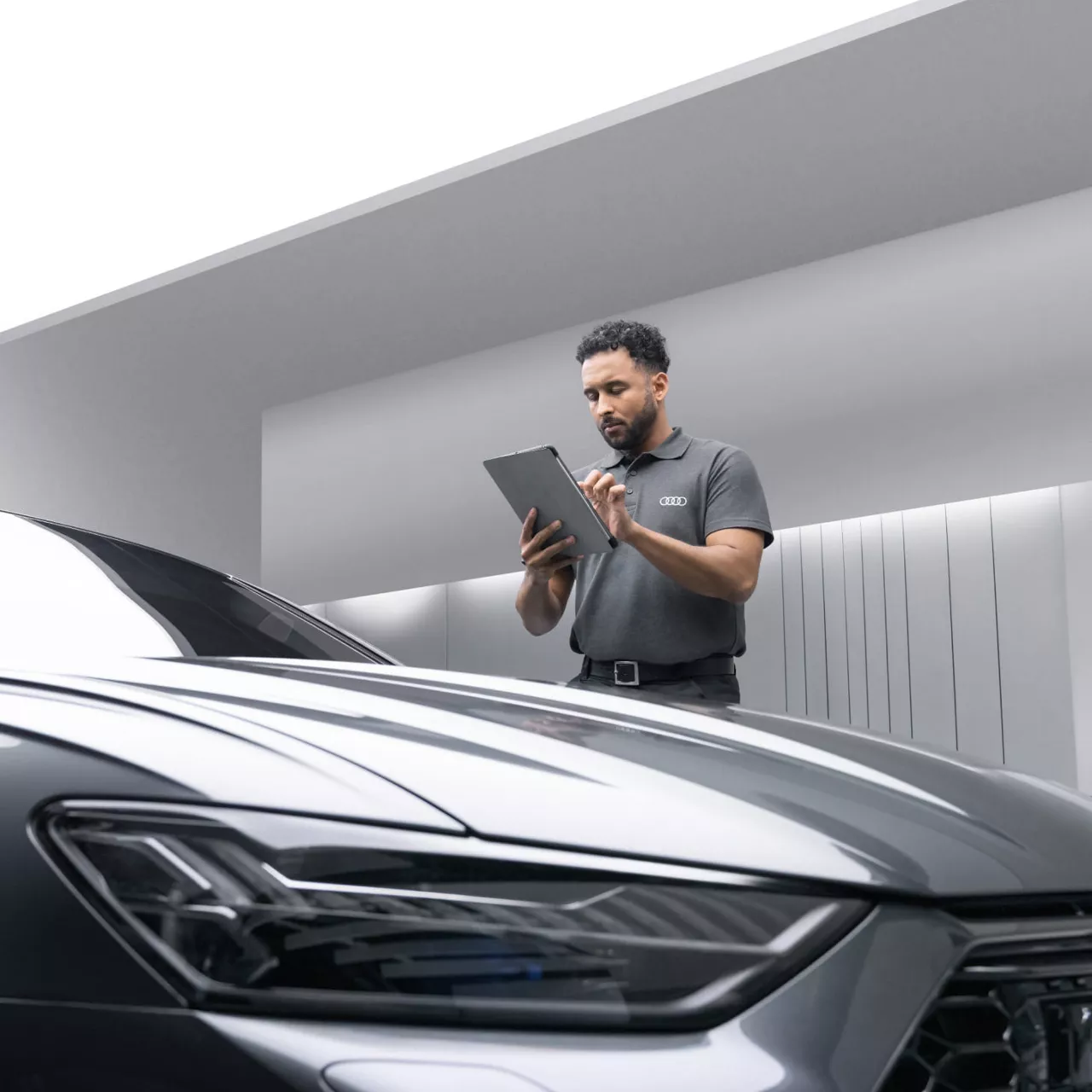 Audi Technician posing in front of an Audi vehicle, whilst taking some notes