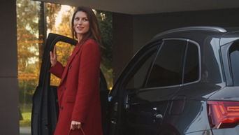 Woman in formal attire posing next to her Audi vehicle