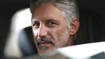 Older gentleman looking at the camera, inside his Audi vehicle