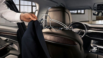 Male hand hanging a suit on the back of the passenger seat, by using an official Audi accessory