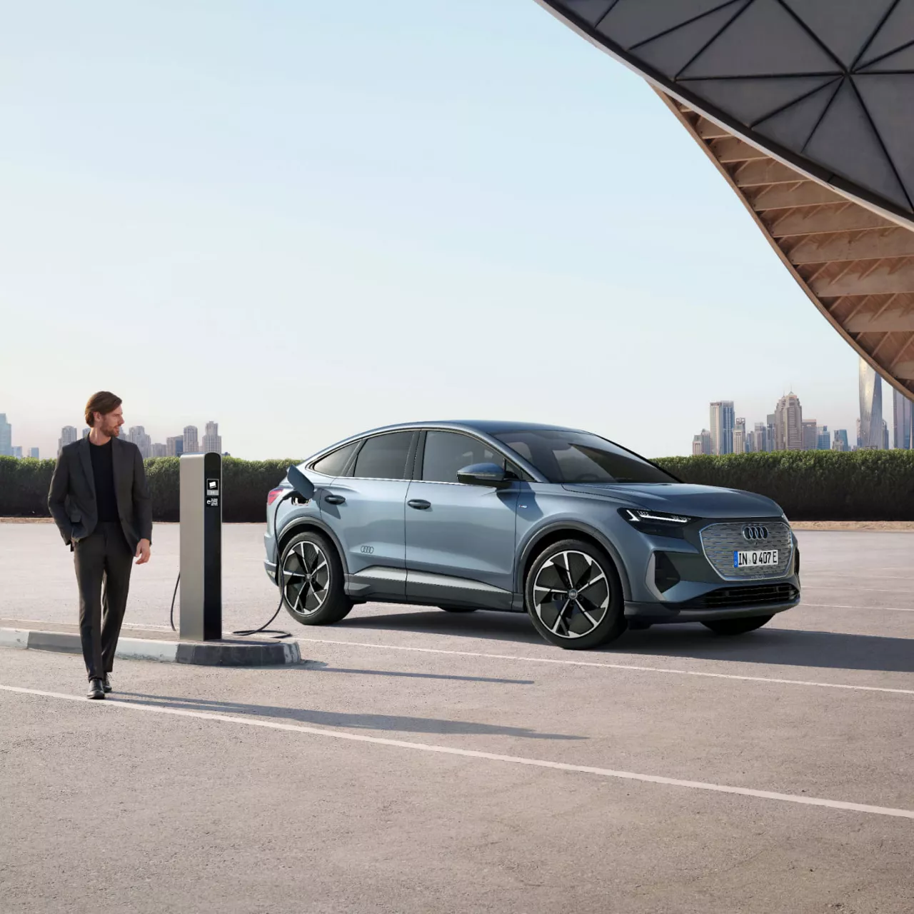 Man walking past an electric Audi vehicle being charged