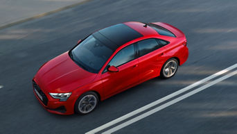 Overhead view of an Audi A3 Saloon cruising on a highway, showcasing its glossy black roof and modern design elements.