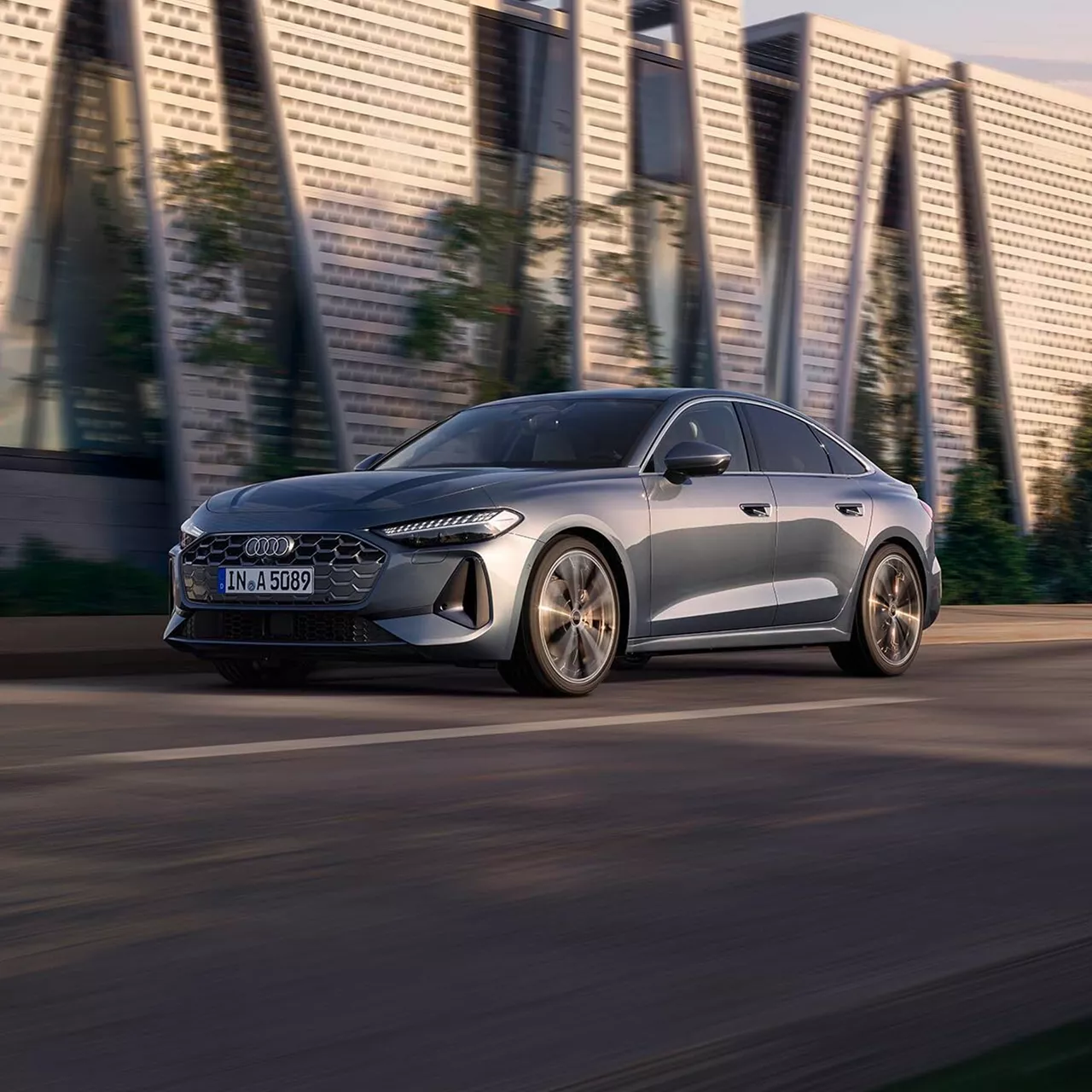 Audi sedan drives along a modern urban street with stylish architecture in the background.