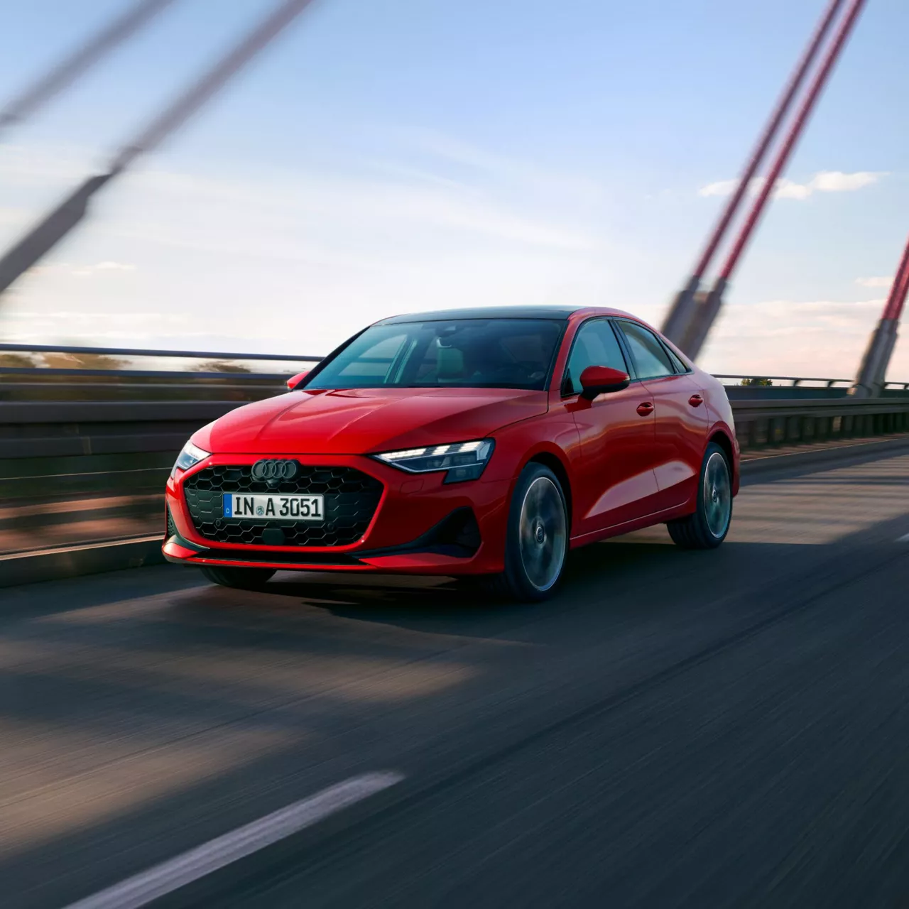 Red Audi A3 Saloon driving on a bridge with motion blur in the background.