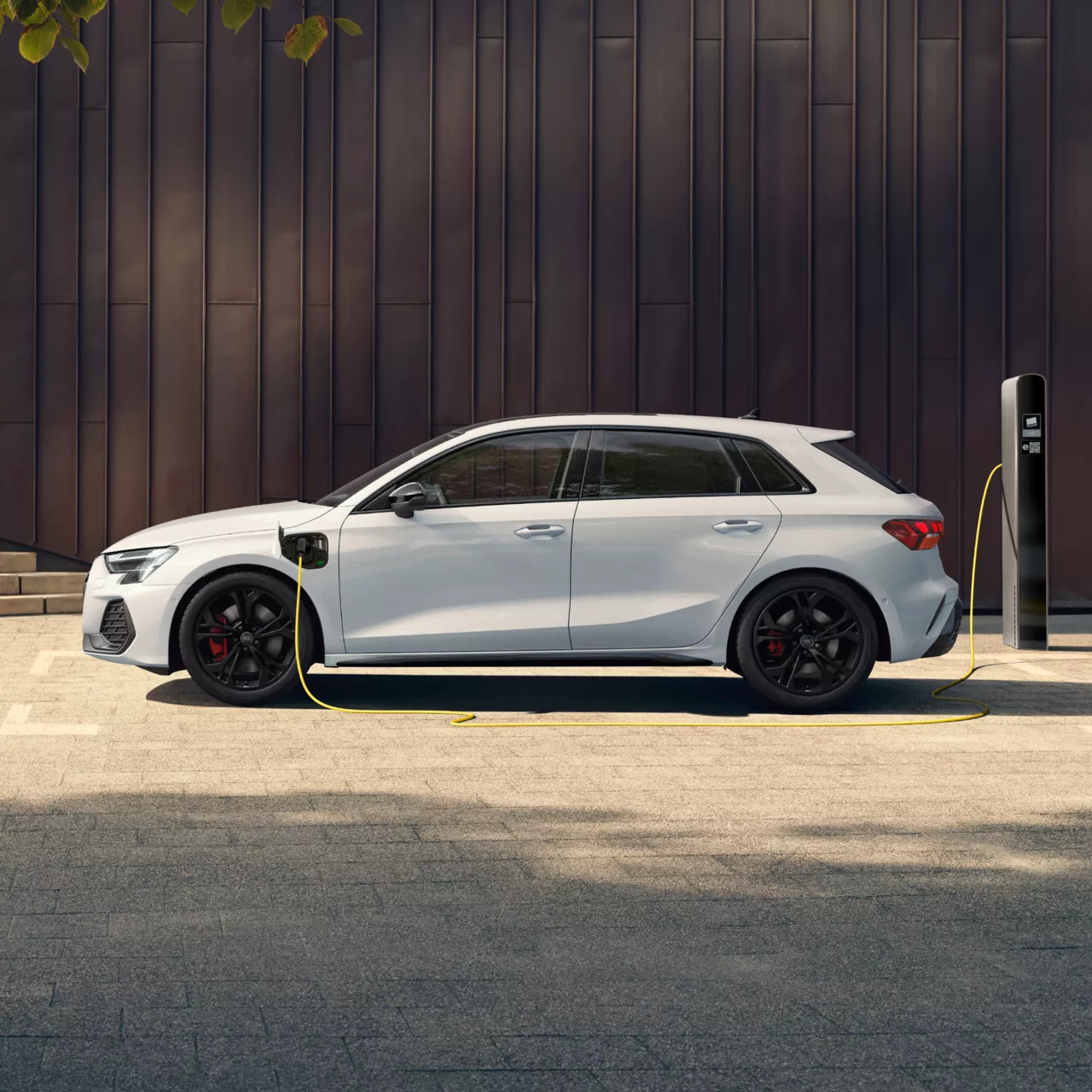 White electric Audi car charging at a charging station.