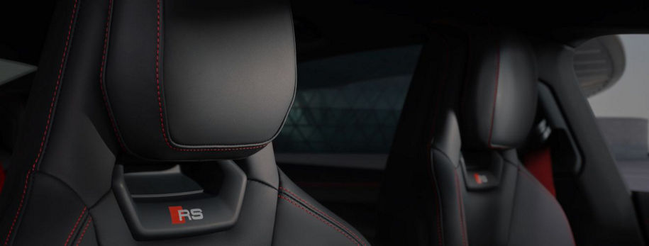 Close-up of two sleek RS car seats with black leather and red stitching, emphasising sporty design and luxury details.