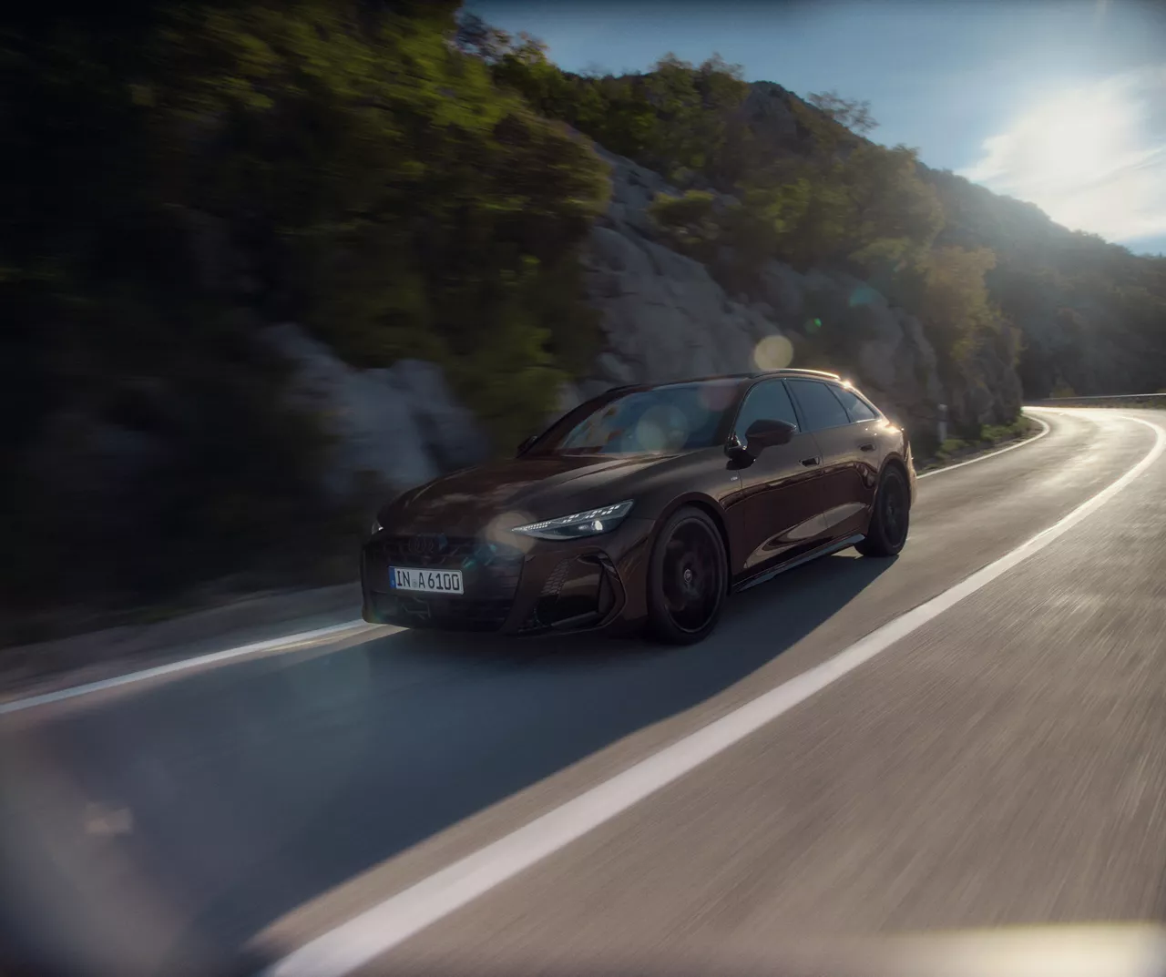 A brown Audi A6 Avant in action driving downhill on a mountain road