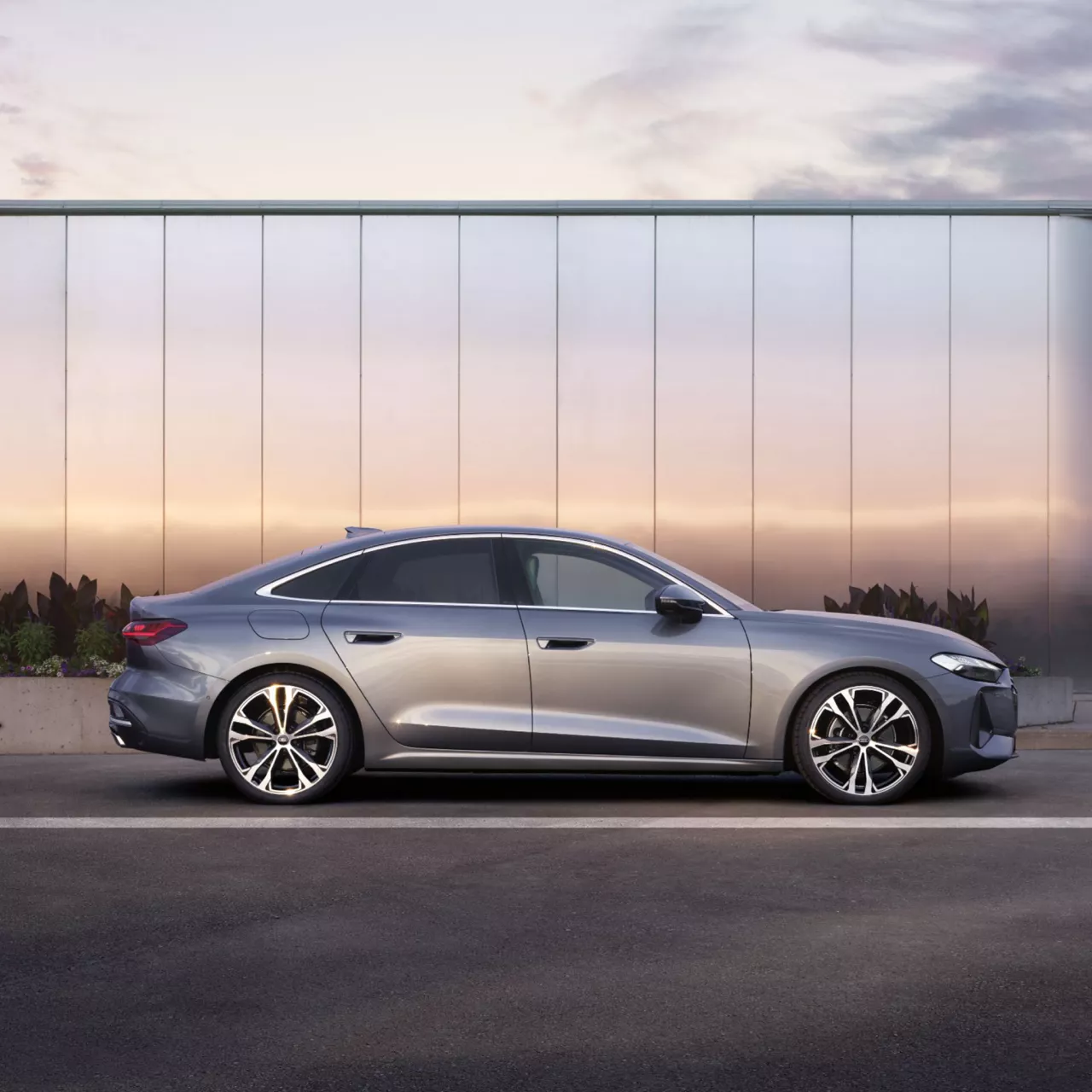 A light grey Audi A5 Saloon parked in front of a metallic wall, sideview