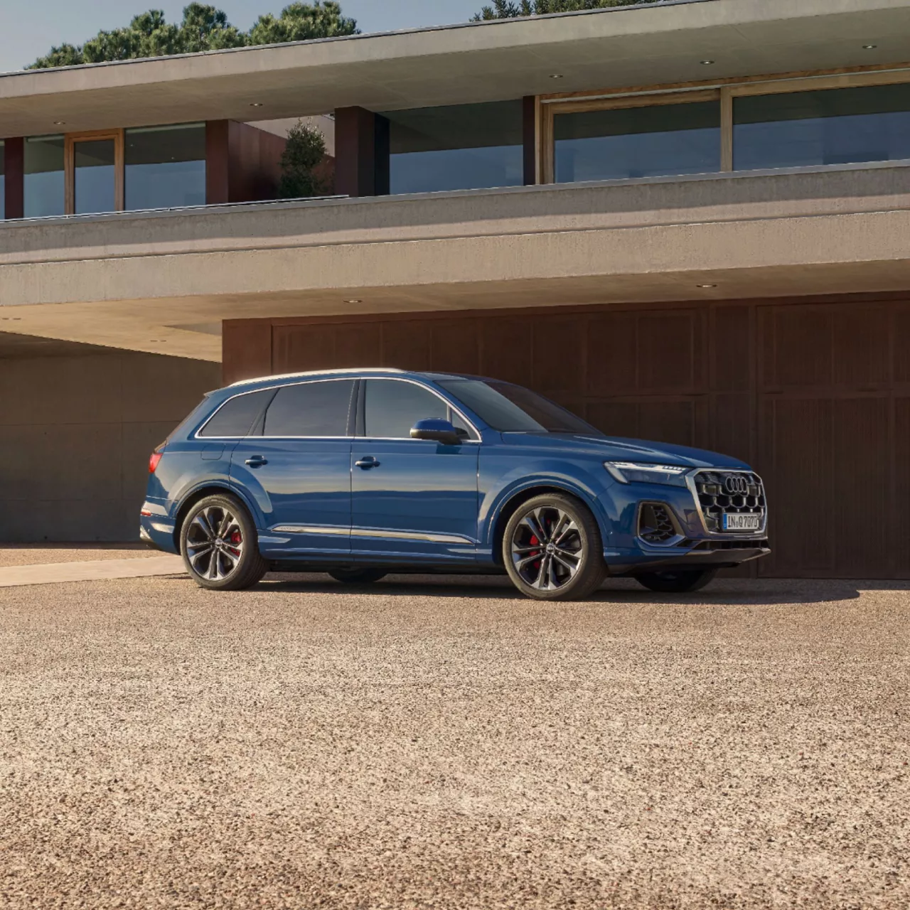 Blue Audi Q7 SUV parked outside a minimal, modern residence