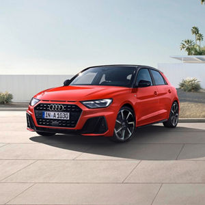 A red Audi A1 Sportback sits on a modern patio, showcasing its sporty design against a minimalist backdrop with palm trees.