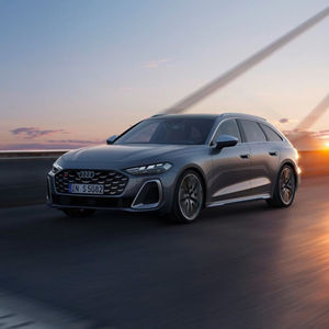 A grey Audi stands in motion against a sunset backdrop, showcasing its aerodynamic design and sporty features.