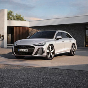 A white Audi A6 e-hybrid parked outside a modern home, showcasing its stylish design and luxury features.