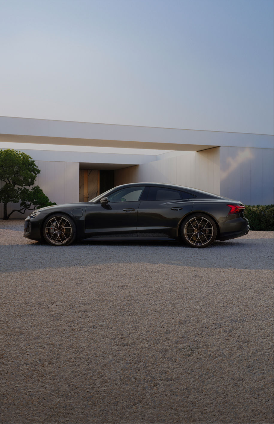 Audi e-tron GT side view on gravel surface in front of a house