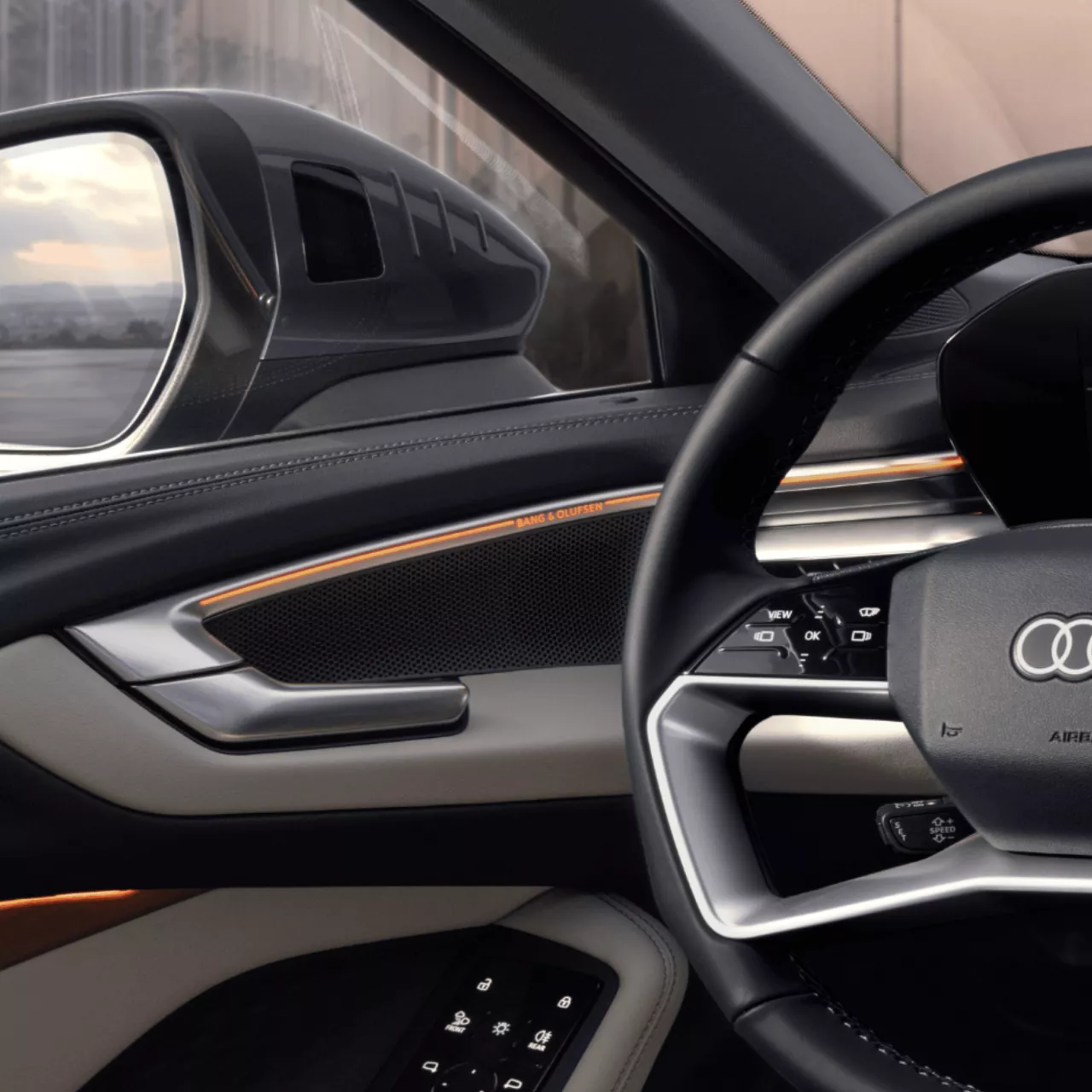 Car's interior with leather steering wheel, Bang & Olufsen speakers, and high-tech controls.