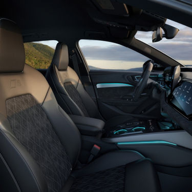 Car interior featuring quilted leather seats with diamond patterns, stylish ambient lighting, and a modern digital dashboard at sunset.