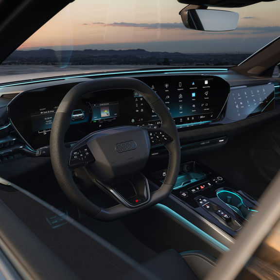 Car dashboard featuring a sleek steering wheel with controls, illuminated digital displays, and ambient blue lighting, conveying modernity.