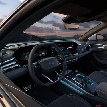 Car interior at sunset, featuring a sleek dashboard with digital displays and ambient lighting.