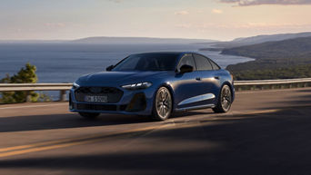 A sleek blue car drives along a coastal road with a scenic view of the ocean and distant hills at sunset, conveying freedom and adventure.